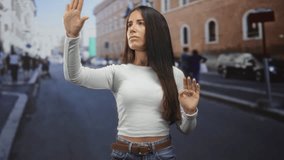 Woman reaching forward with hands raised and palms out as if touching an invisible screen on a city street; focus concentration. - Powered by Shutterstock - Get 15% off with code: PIKWIZARD15