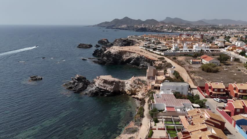 Aerial view of rocky coastline in Spain with cliffs, houses and clear Mediterranean Sea. Scenic coastal landscape and travel destination.