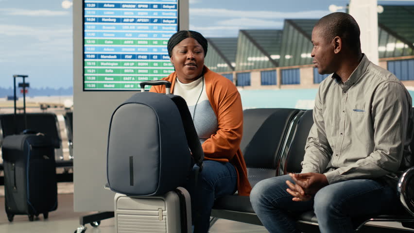 Airport departure area lounge, young family traveling, teenager and parents in good mood, preparing for boarding during family holiday trip. Black passengers with backpacks, international voyage.