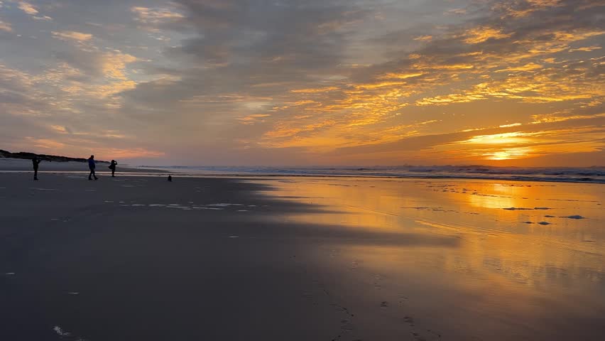 Golden sunset over the Atlantic in Portugal with a family in silhouette