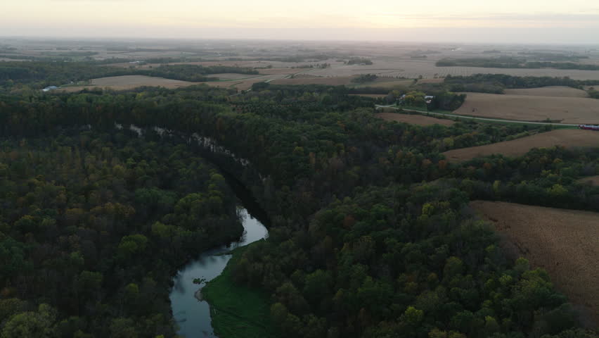 Winding North branch waterway flowing through forest and farmland in Root River Park Minnesota, aerial pullback