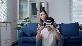 Young Asian couple wearing virtual reality headsets, laughing and enjoying immersive gaming experience together in cozy living room, sharing digital entertainment and technological connection - Powered by Shutterstock - Get 15% off with code: PIKWIZARD15
