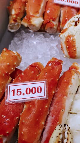 Close-up camera pans across cooked king crab legs displayed on ice with price tags