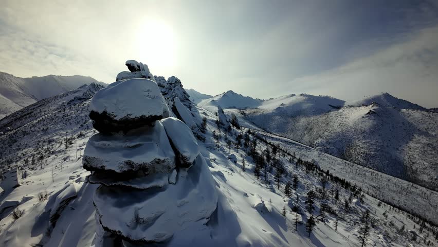 Flying a drone over snowy mountains and rock formations during daylight hours