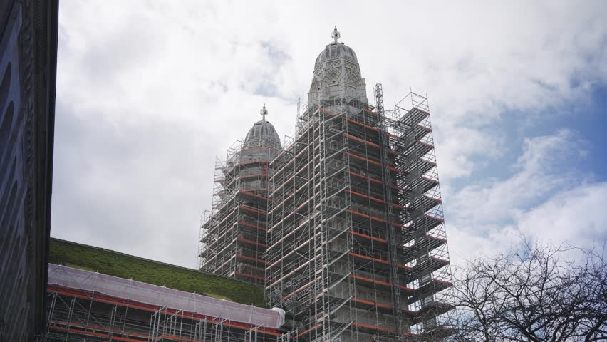 Historic grossmunster church undergoing restoration with extensive scaffolding covering its iconic towers