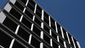 Close-up perspective of a contemporary business building exterior featuring a repetitive grid pattern of white frames and dark windows. The shot highlights the clean lines and geometric design of modern urban architecture. - Powered by Shutterstock - Get 15% off with code: PIKWIZARD15
