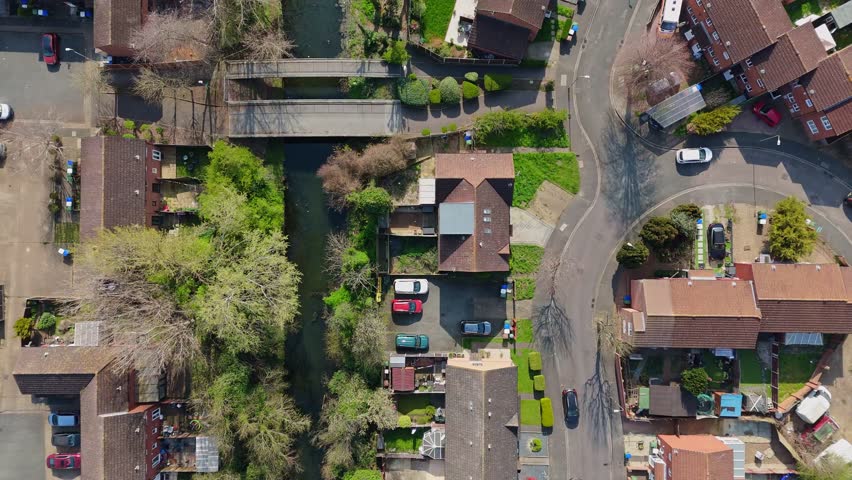 Top-down drone view of houses along a canal with bridges, taken in daytime