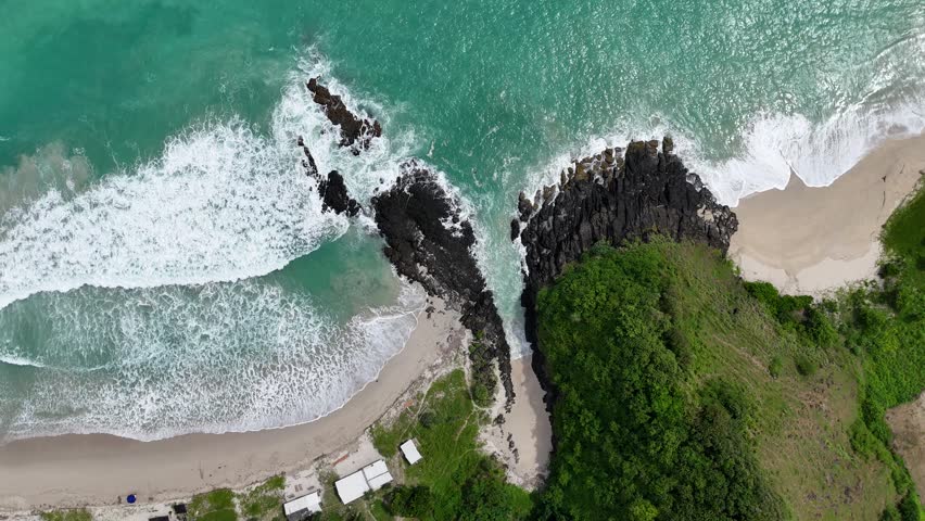 Aerial View of Tropical Coastal Landscape with Crashing Ocean Waves on Sandy Beach and Rocky Shoreline, Lush Green Cliff and Clear Turquoise Water