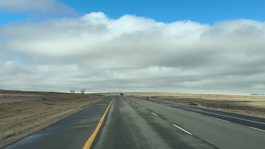 Forward driving view on rural highway during springtime with wide open road and natural terrain