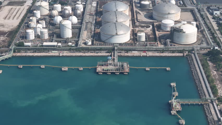 Large industrial petroleum refinery plant and oil storage tank farm at maritime loading terminal. Global energy logistics, liquid cargo supply chain, and fuel distribution concept.	
