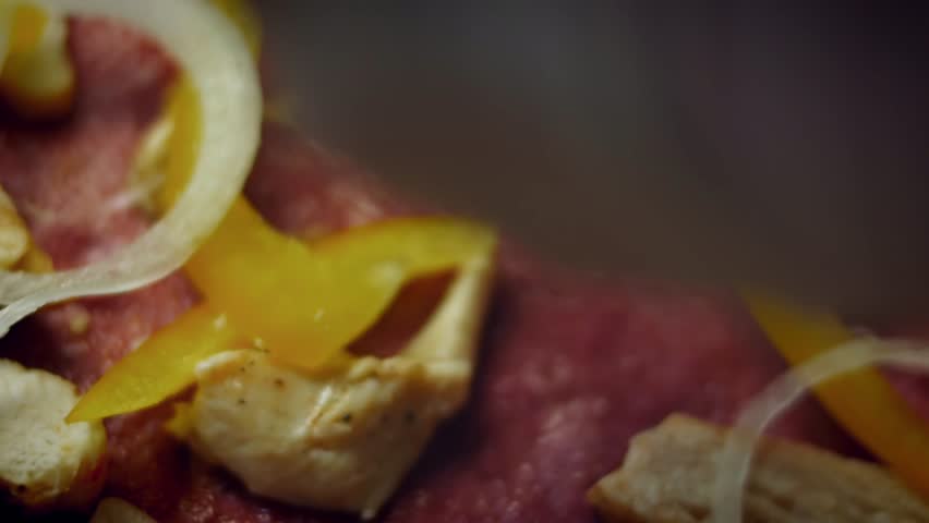 Close up of onions placed on beet pizza dough alongside other ingredients