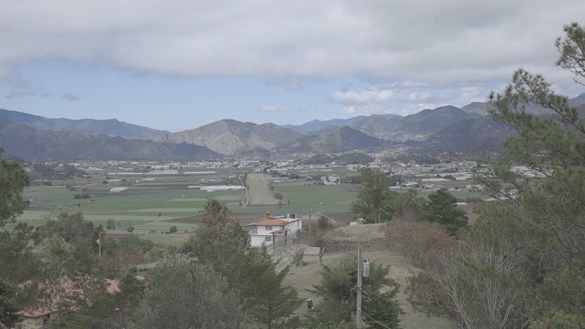 Scenic view of a picturesque valley surrounded by majestic mountains, under a cloudy sky
