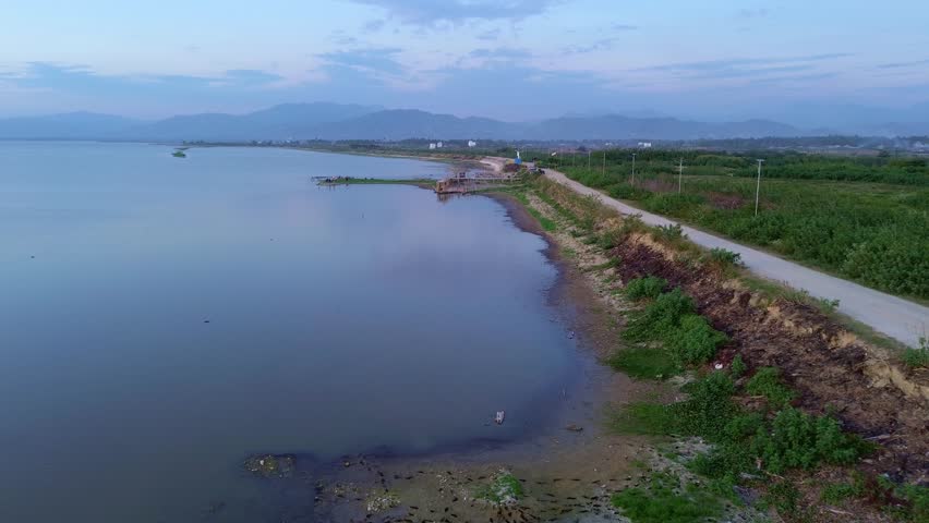 Aerial View of Lake and Dirt Road with Mountains at Dusk