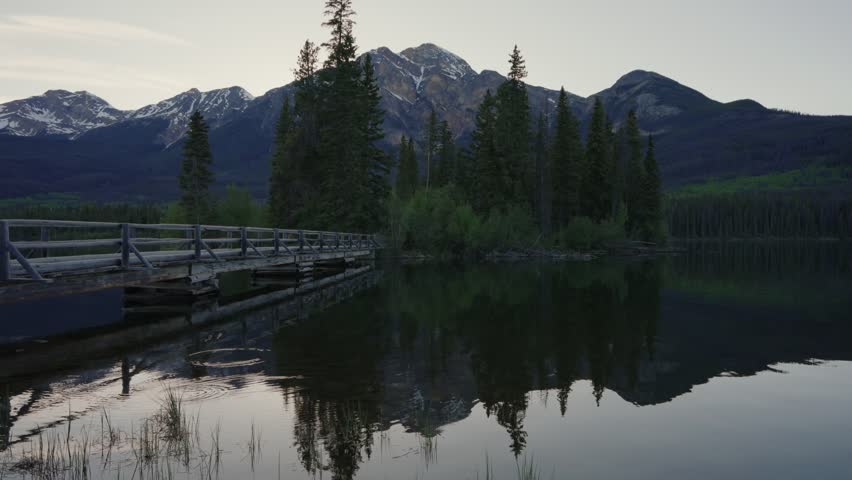 Pyramid Lake with calm water reflecting surrounding pine trees and mountains in Jasper National Park, Canada