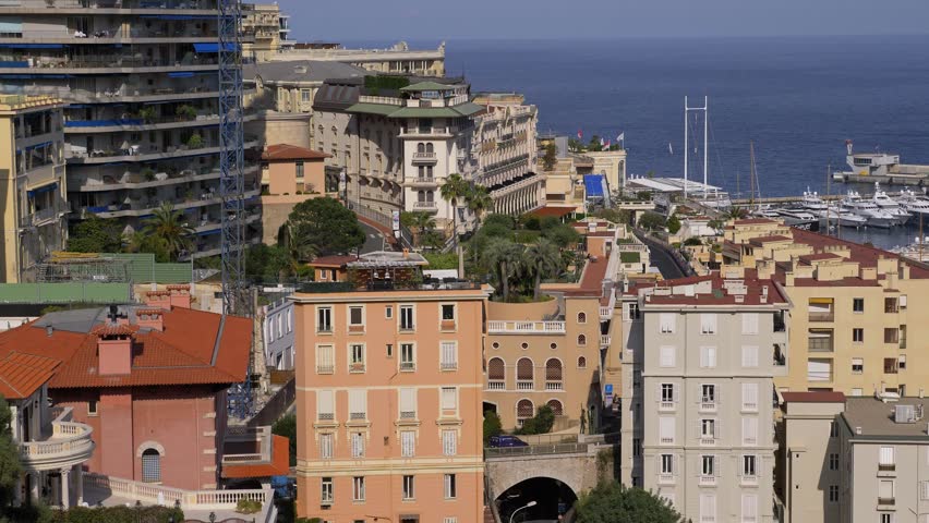 4K footage of Monaco cityscape overlooking the harbor filled with luxury yachts. Colorful Mediterranean buildings rise above the marina with elegant architecture and coastal views of the French Riviera. Scenic urban landscape combining historic charm and modern luxury lifestyle in Monte Carlo. Monaco 7 May 2019 