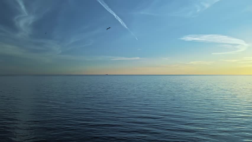 A serene ocean horizon at sunset with subtle ripples on the water and a clear sky, an ideal backdrop for tranquil and expansive visuals