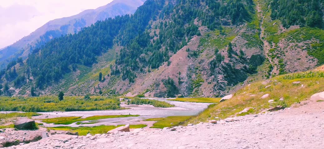 "A stunning view of the fast-flowing Kunhar River meandering through the lush green mountains of the Kaghan Valley in Naran, Khyber Pakhtunkhwa (KPK), Pakistan