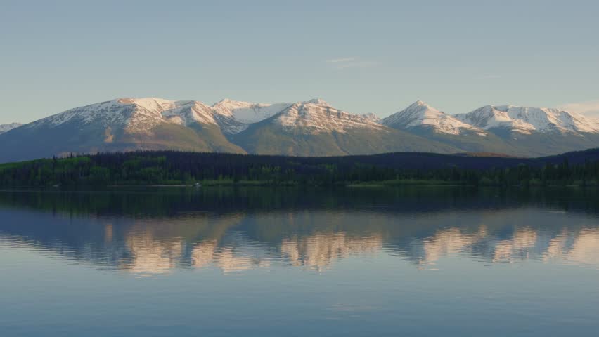 Pyramid Lake with snow capped mountains and forest reflecting in calm water in Jasper National Park, Canada