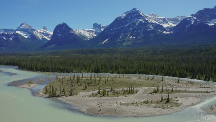 Athabasca river winding through forests with snow capped Rocky Mountains in Jasper National Park, Canada
