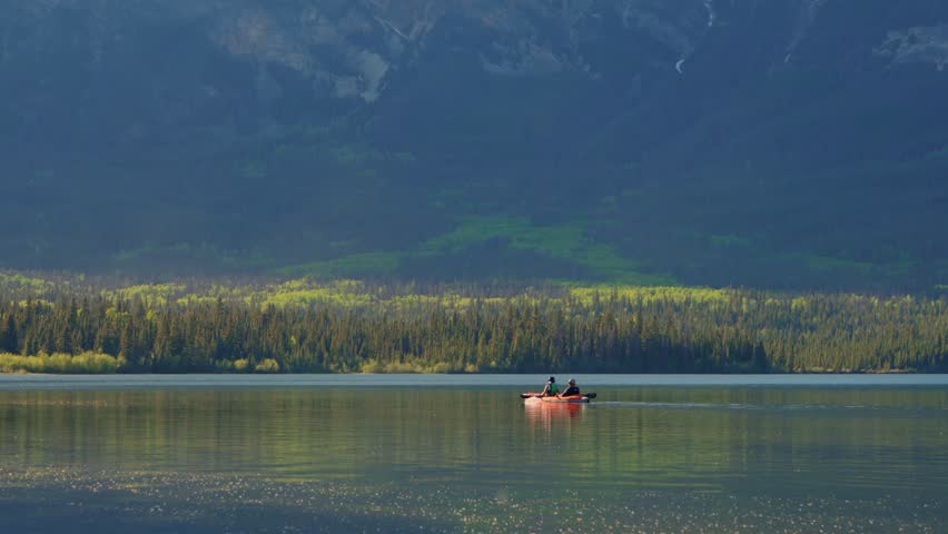 Two people enjoying scenic kayaking on Pyramid Lake reflecting mountains and forest in Jasper national park, Canada