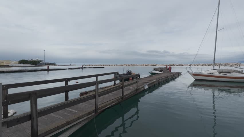 Old Wooden Dock With Sailboats in Calm Harbor Under Clouds
