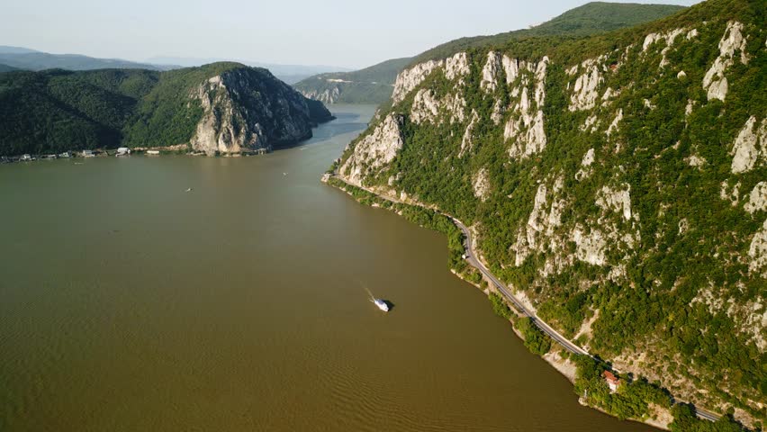 Aerial Reveal of Iron Gates Gorge on the Danube River in Romania — Dramatic Cliffs, Winding Road and Boat on Water