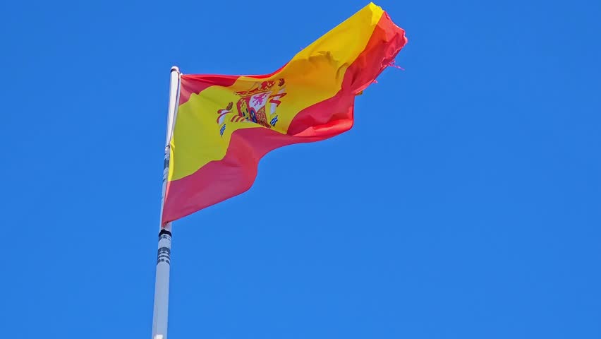 Spanish flag proudly waving with the royal coat of arms , symbolizing national identity, heritage, patriotism, pride and european unity against a vibrant blue backdrop