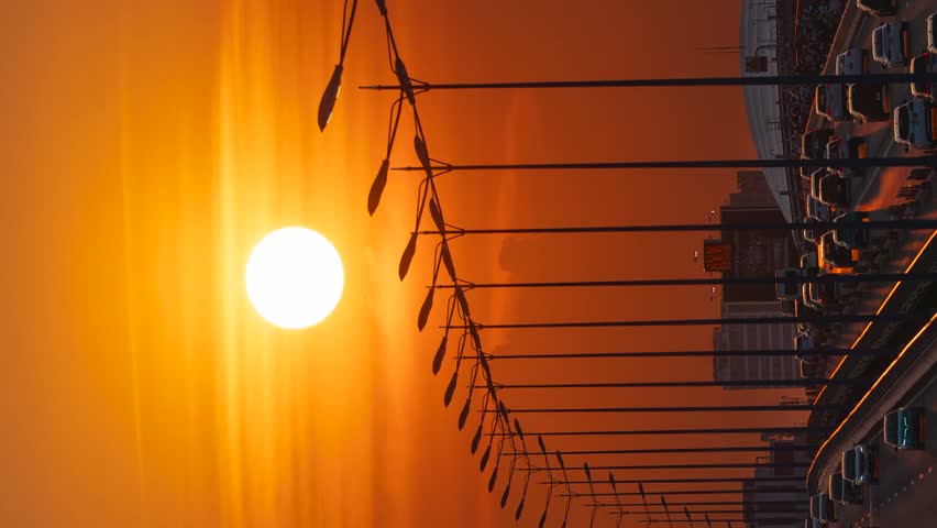 vertical clip. A vibrant 4K sunset timelapse capturing golden hour traffic flowing across a bridge in Ho Chi Minh City, featuring rhythmic light poles.