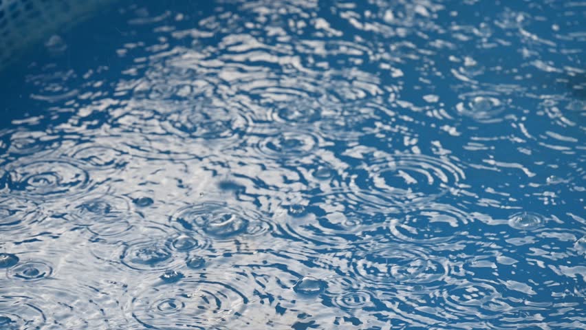close up of blue water in swimming pool with rain drops