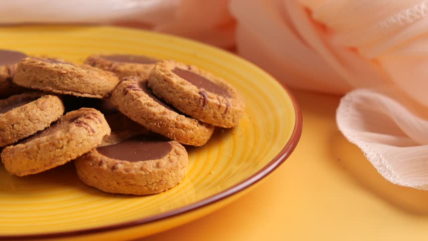 A close up view of delicious chocolate cookies on yellow plate, snack food for tea time and coffee break, sweet biscuit for dessert.