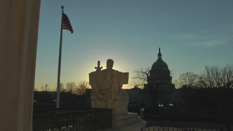 WASHINGTON, DC - JAN. 29, 2012: Supreme Court's Authority of Law marble faces the US Capitol and US Senate.  Sun setting, U.S. Capitol, American Flag.  Washington, DC.  