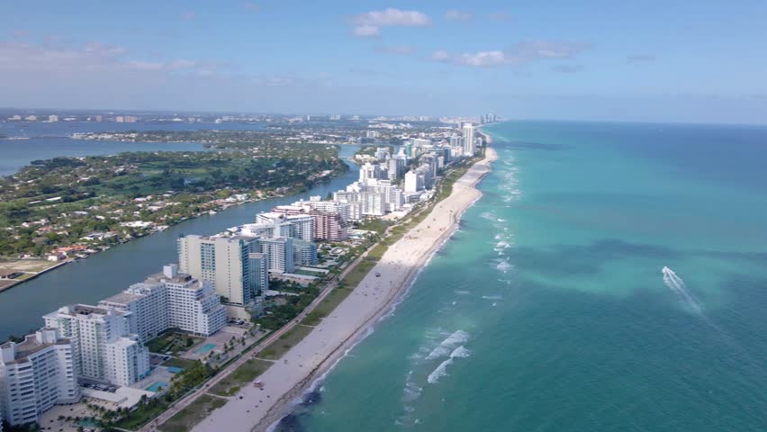 Aerial view of Miami Beach coastline with high-rise buildings and turquoise ocean waves