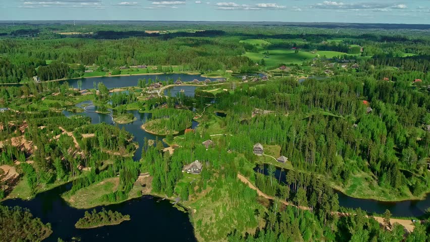 Aerial view of luxury eco resort with wooden villas nestled in lush green forest by tranquil lake waters