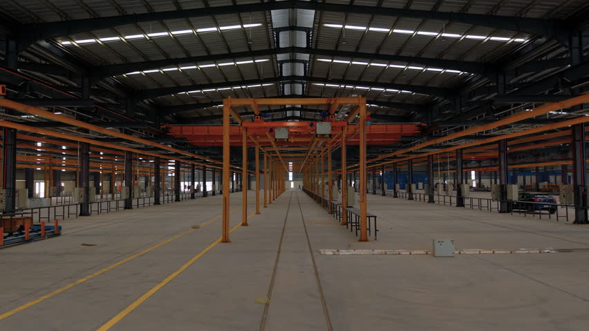 Wide interior shot of a spacious empty industrial warehouse with overhead cranes and production lines. Ideal for engineering, logistics, and manufacturing concepts.