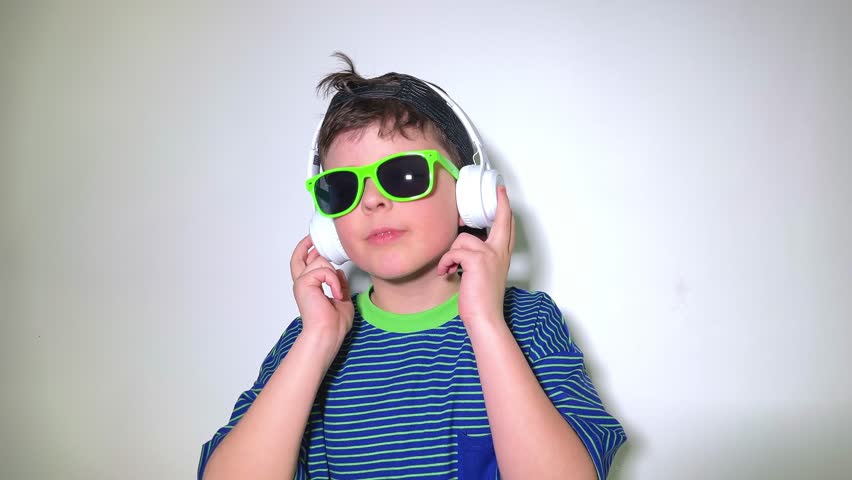 Cute little boy dancing with sunglasses and headphones