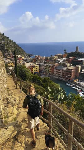 Man enjoying panoramic view of Vernazza village from above in Cinque Terre Italy.
Back view of traveler admiring scenic coastal town and sea from high viewpoint.