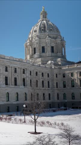 State Capitol in St Paul Minnesota shows its design while surrounded by snow and clear sky on a sunny day.
