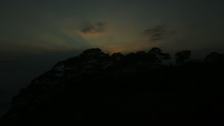 Timelapse footage of forested mountains above a sea of ​​clouds at sunrise.