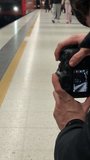 Vertical screen Videographer filming in metro station capturing urban movement trains passing and people commuting in dynamic city environment - Powered by Shutterstock - Get 15% off with code: PIKWIZARD15