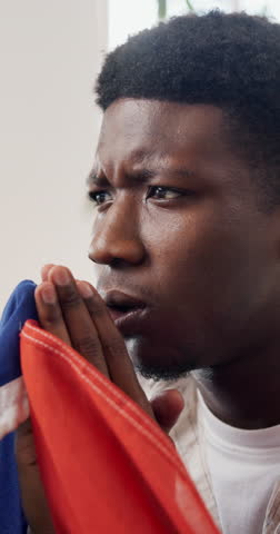 Disappointment, worry or black man in home with soccer game, match loss or upset in sports tournament. Anxiety, flag or football fan with frustration, score mistake or event results in South Africa.