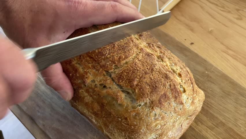 Man cutting freshly made sourdough bread in the kitchen