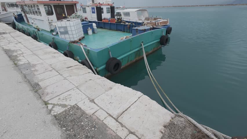 Tugboat Moored at Dock With Ropes and Equipment in Quiet Harbor
