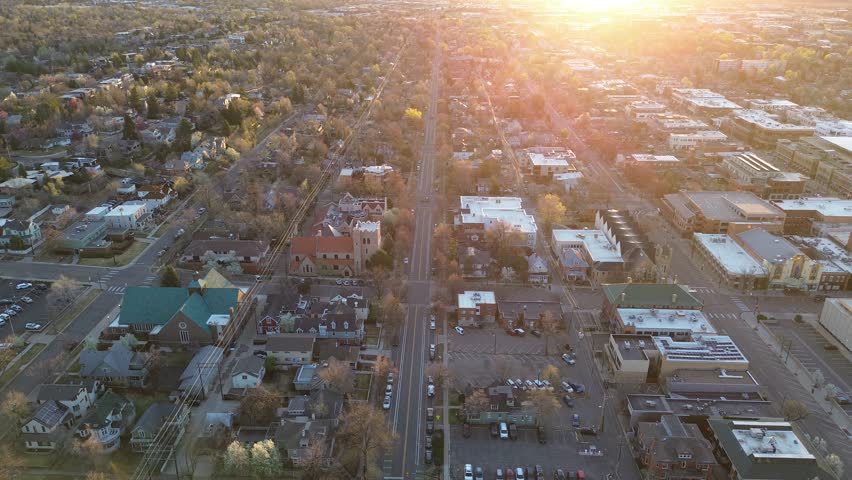 Central Boulder neighborhoods west of Pearl Street show quiet streets, churches, low commercial buildings arranged in clean grid. Rooftops, chimneys, bare branches, muted siding, Colorado. USA