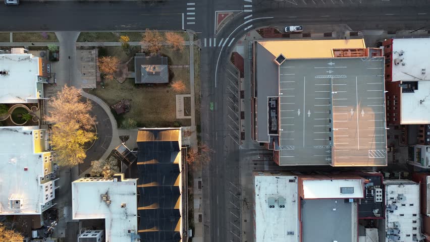 Central Boulder intersection near Walnut Street and downtown parking garage shows mixed commercial, residential edges in clean grid. Warm light outlines flat roofs, lane markings, bare trees, CO. USA