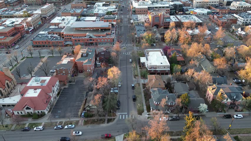 Downtown Boulder blocks near Pearl and Walnut Street form tight grid transitioning toward residential by Front Range foothills. Warm light flat roofs, pitched shingles, bare trees, brick textures. USA