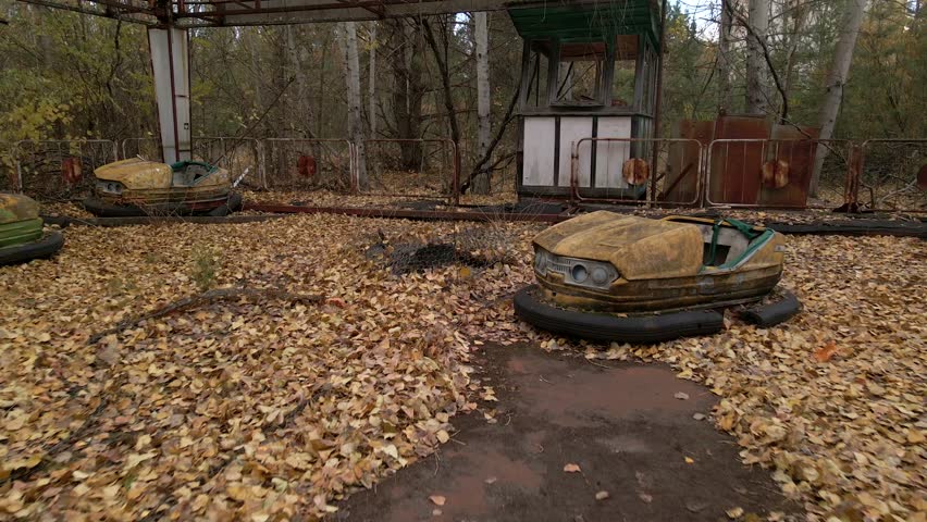 Abandoned bumper cars in the amusement park of ghost town Pripyat. A cinematic shot of rusty old bumper cars covered in fallen autumn leaves at the abandoned amusement park in the Chernobyl exclusion zone