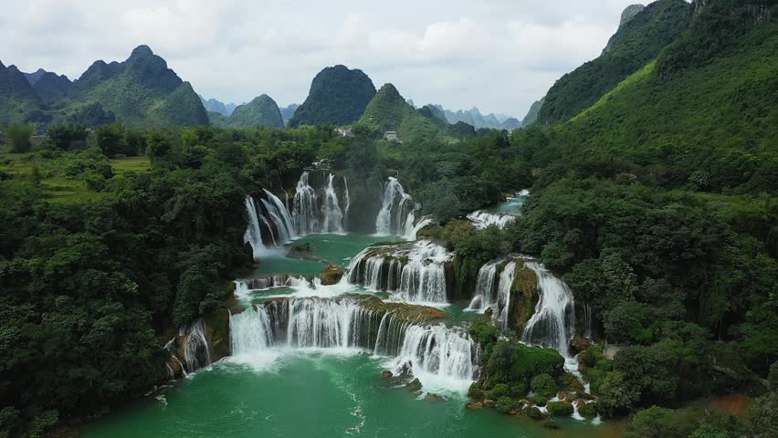 Aerial view of Ban Gioc Waterfall cascading through lush green mountains and dense forest, creating a dramatic natural landscape in northern Vietnam.