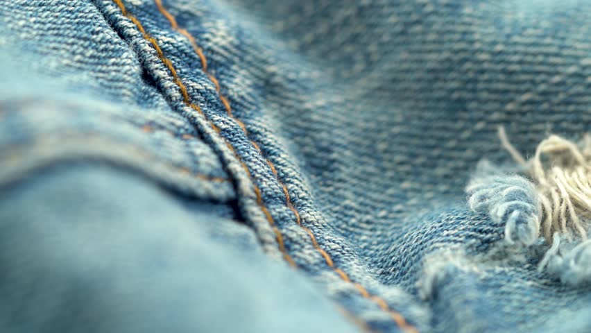 Close up of torn denim fabric texture with frayed threads