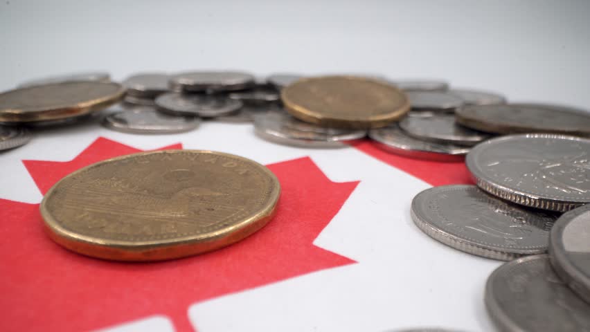 Close up of Canadian one dollar coin on flag with scattered coins
