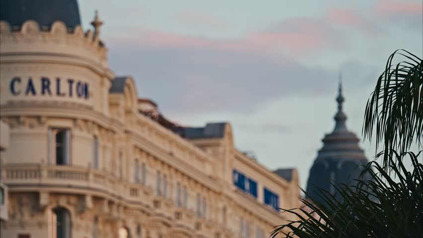 Carlton hotel building facade with ornate architecture during sunset with palm trees in foreground.